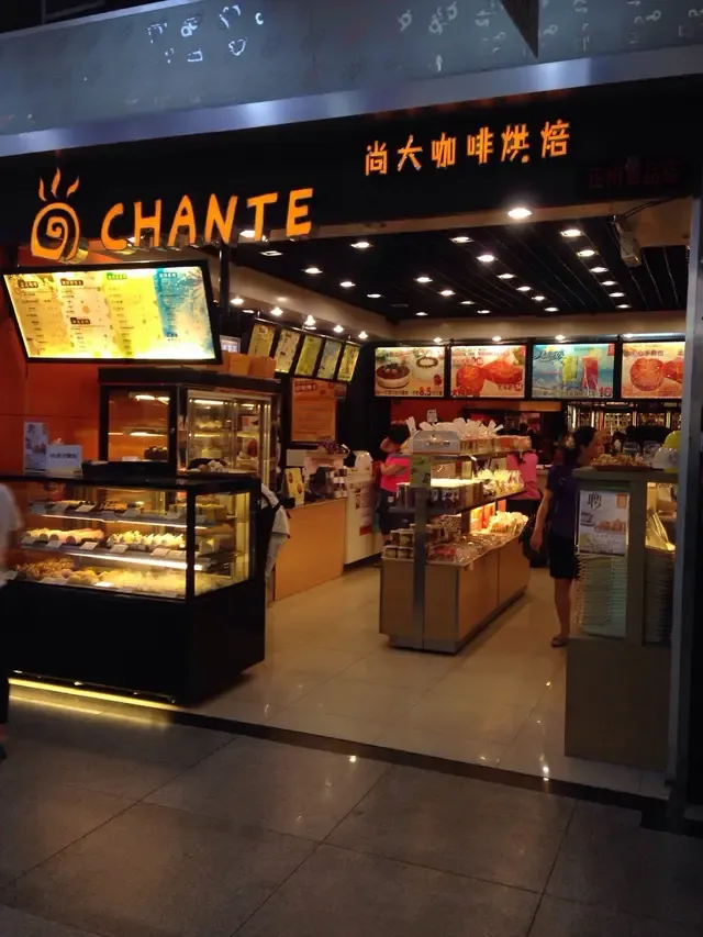 chante bakery storefront with illuminated display cases and menu boards at night., 尚大咖啡烘焙, guangzhou
