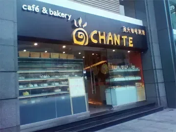 café and bakery storefront with illuminated signage and display windows showing pastries and goods., 尚大咖啡烘焙, guangzhou