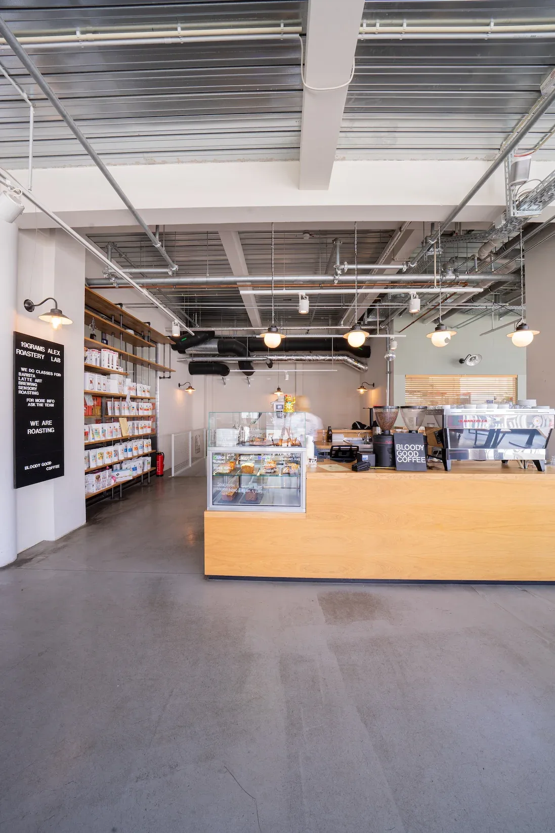 modern coffee shop interior with wooden counter and industrial ceiling design., 19grams alex – coffee roastery, berlin