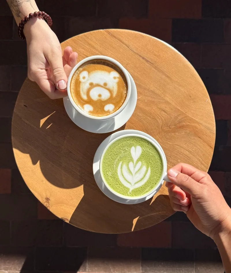 two specialty coffee drinks with latte art on wooden table held by hands., 35 north coffee, santa fe