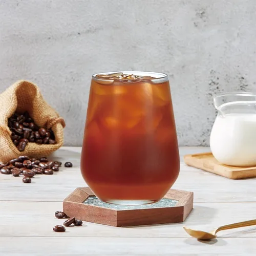 iced coffee drink with coffee beans, cream pitcher, and wooden coaster on white surface., 85度c咖啡蛋糕烘焙專賣店, xiamen
