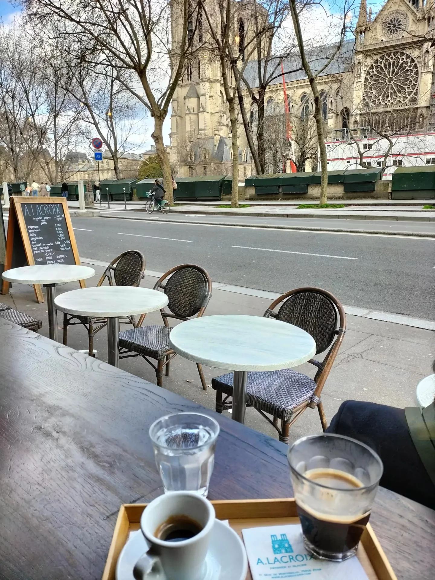 outdoor café seating with cathedral view, coffee drinks, and bare trees., a. lacroix pâtissier, paris