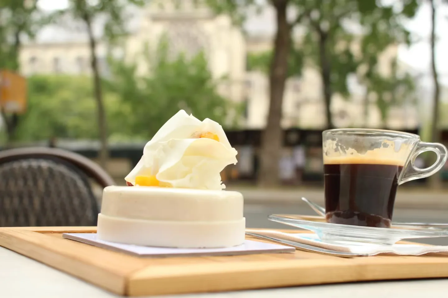 cream dessert and dark coffee on wooden table overlooking park., a. lacroix pâtissier, paris