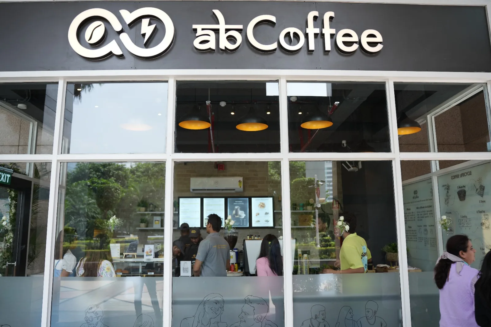 modern coffee shop storefront with large windows and golden pendant lights inside., abcoffee dlf cyber greens, gurugram