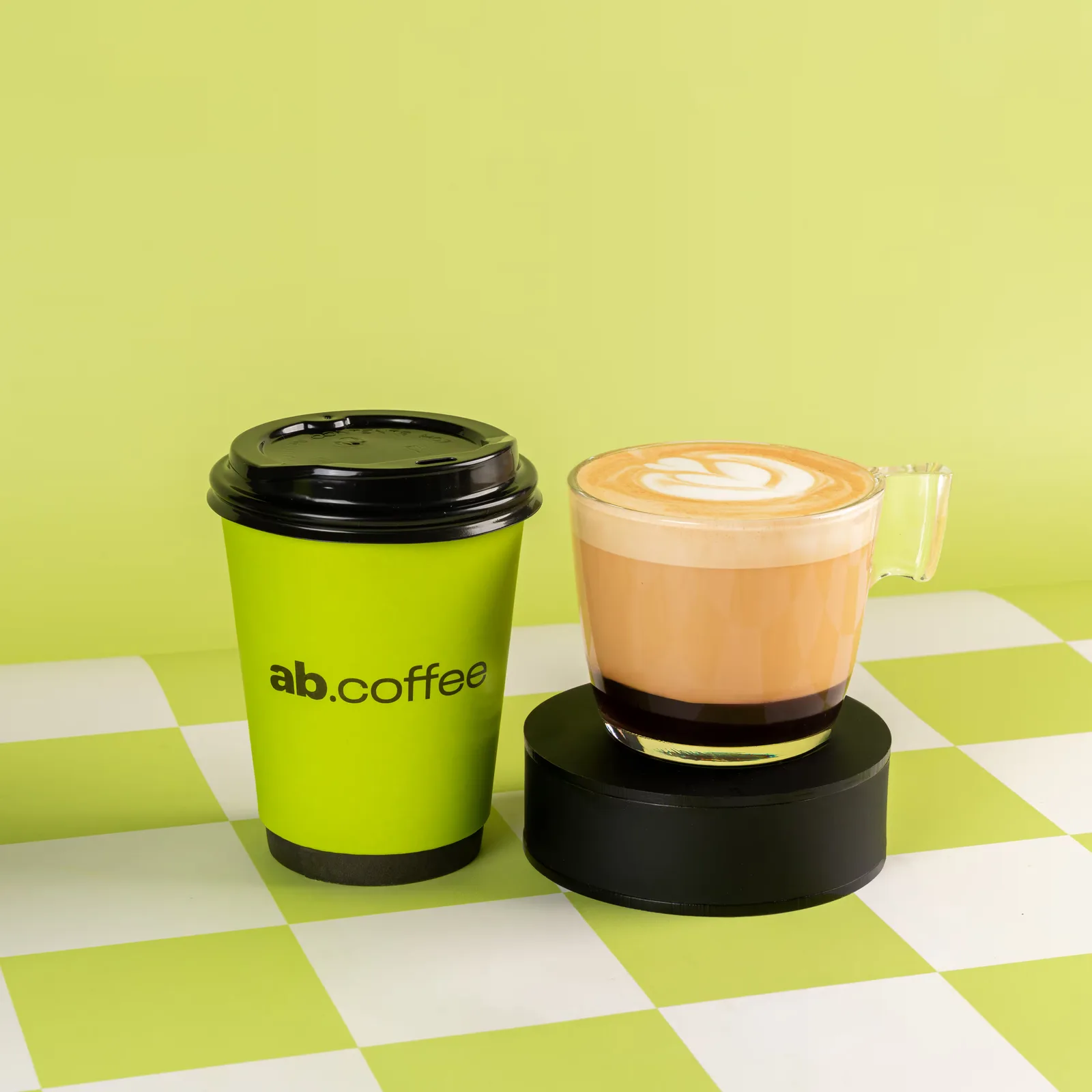ab.coffee branded cup and latte with latte art on checkered surface., abcoffee dlf cyber greens, gurugram