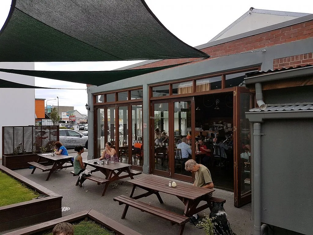outdoor café patio with picnic tables, shade sails, and indoor seating visible through windows., addington coffee co-op, chri
