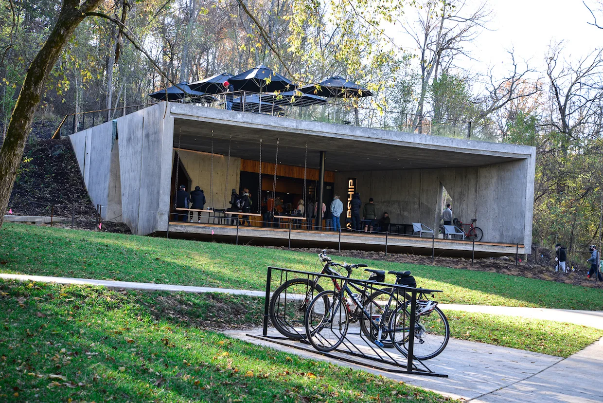 modern concrete pavilion with bikes parked, woodland setting, visitors inside structure., airship coffee at coler, bentonvill