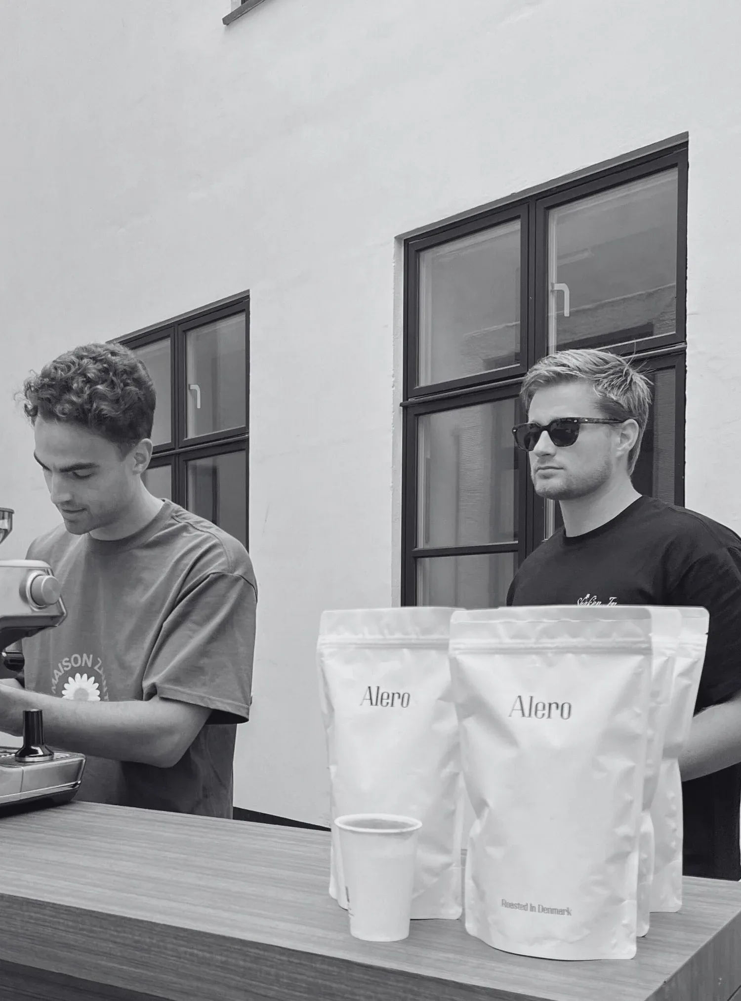 two men at counter with alero branded packaging and white cups displayed., alero coffee, new york city