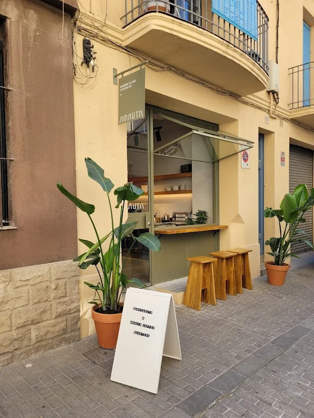 small storefront café with wooden stools, potted plants, and sidewalk signage., amauta coffee, badalona
