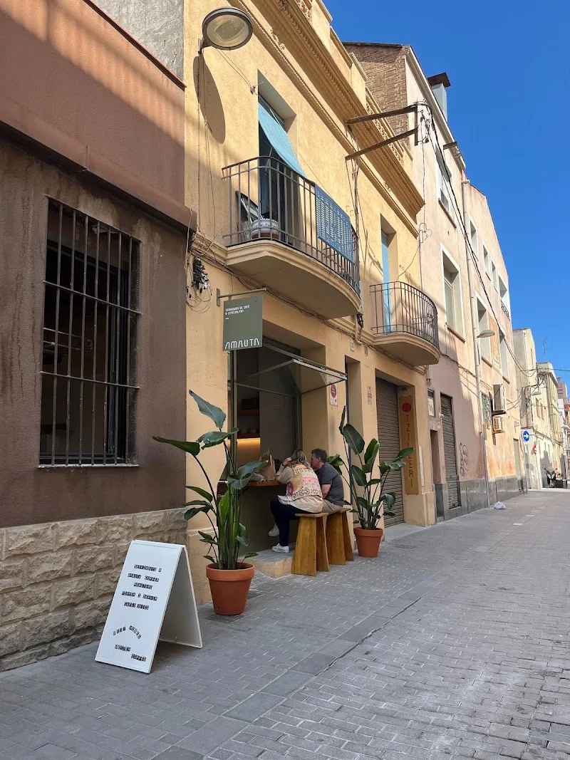 european street storefront with potted plants and seated customer outside., amauta coffee, badalona