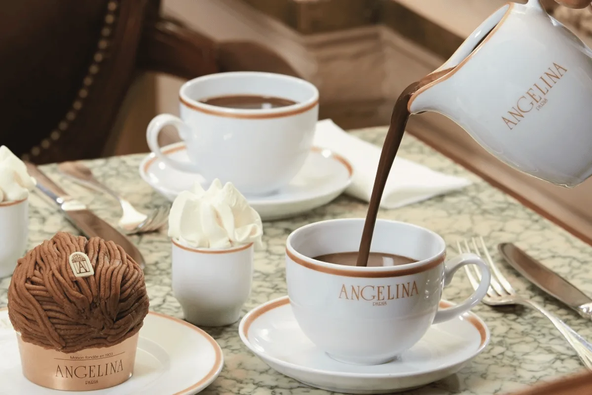 angelina hot chocolate being poured into a cup at a marble table setting., angelina, paris