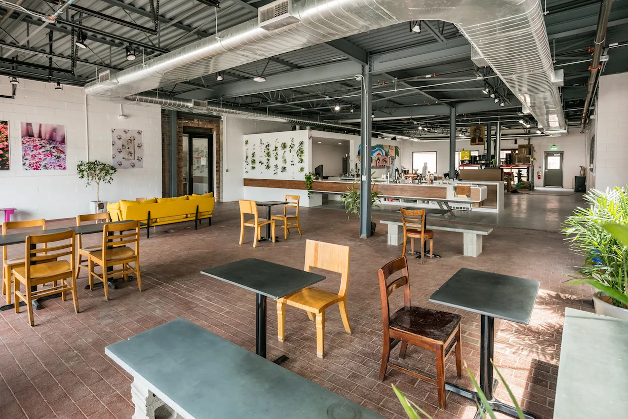 modern warehouse café with wooden chairs, yellow sofa, and green-topped tables., anthology coffee, detroit
