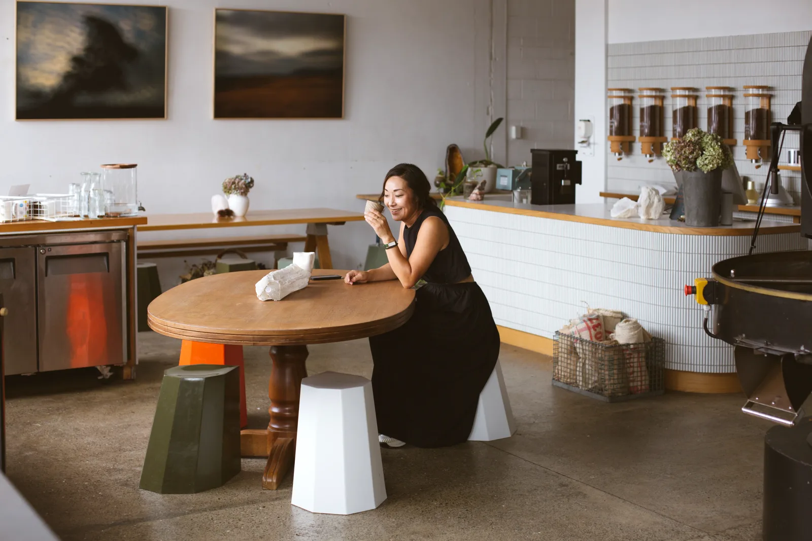 woman seated at round wooden table in modern minimalist cafe interior., ark coffee company, auckland