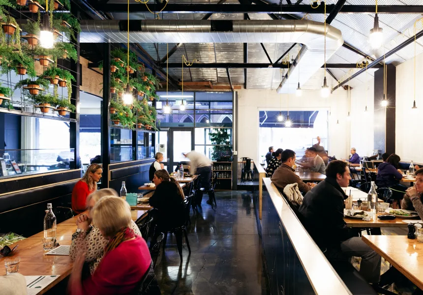 modern restaurant interior with diners seated at tables, green wall plants, and skylights., axil coffee roasters hawthorn, ha