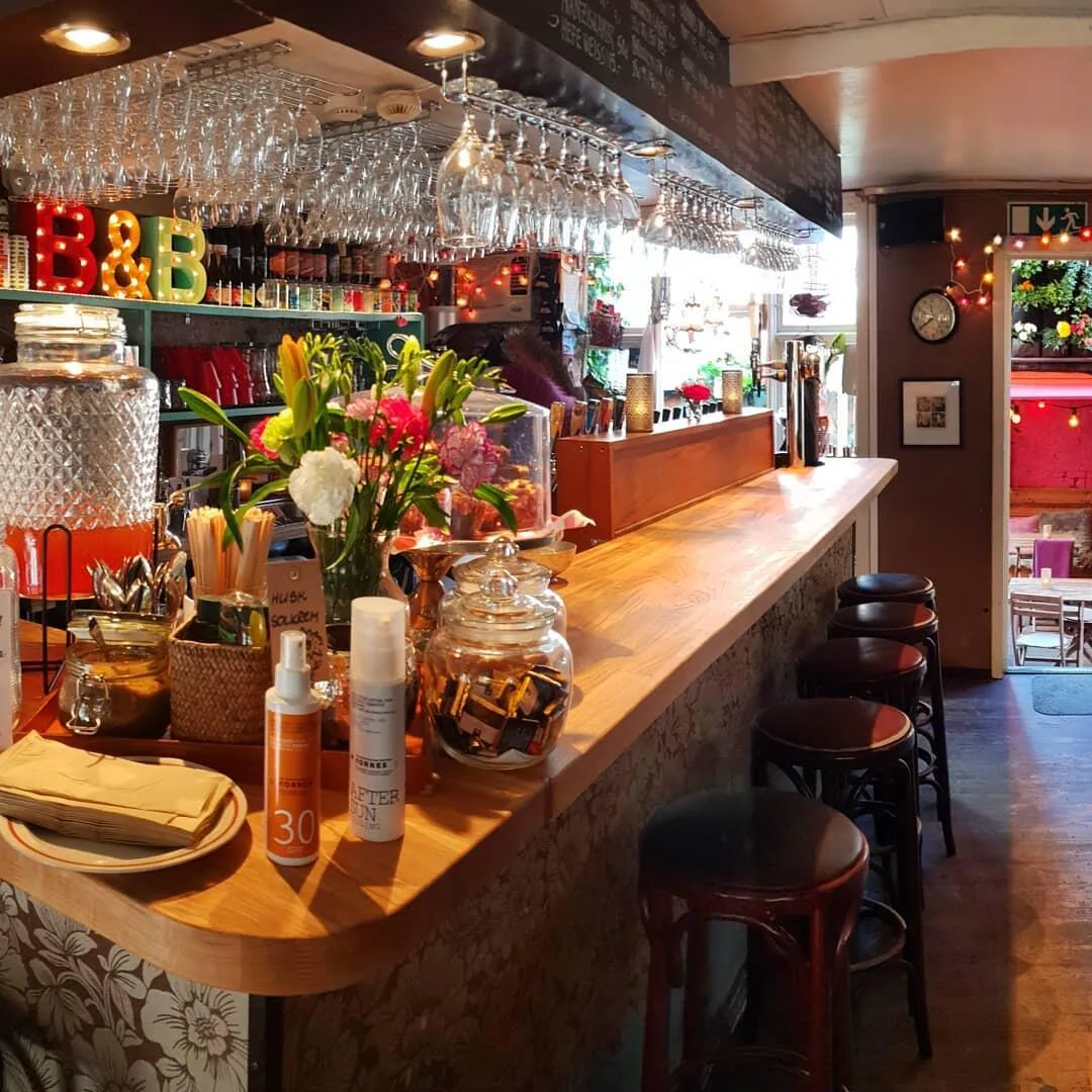 vibrant bar interior with neon signage, wine glasses, fresh flowers, and bar seating., bøker og børst, stavanger