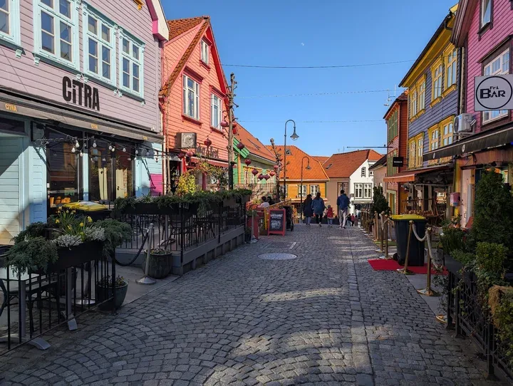 colorful historic wooden buildings line a charming cobblestone pedestrian street., bøker og børst, stavanger