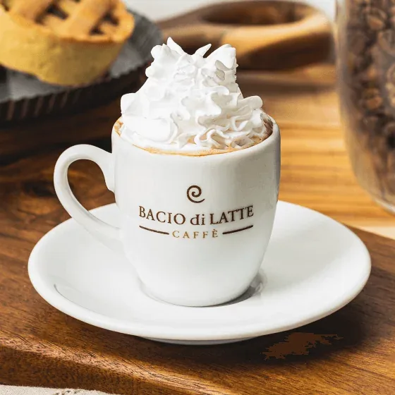 whipped cream topped coffee in branded bacio di latte cup with pastries nearby., bacio di latte, niterói