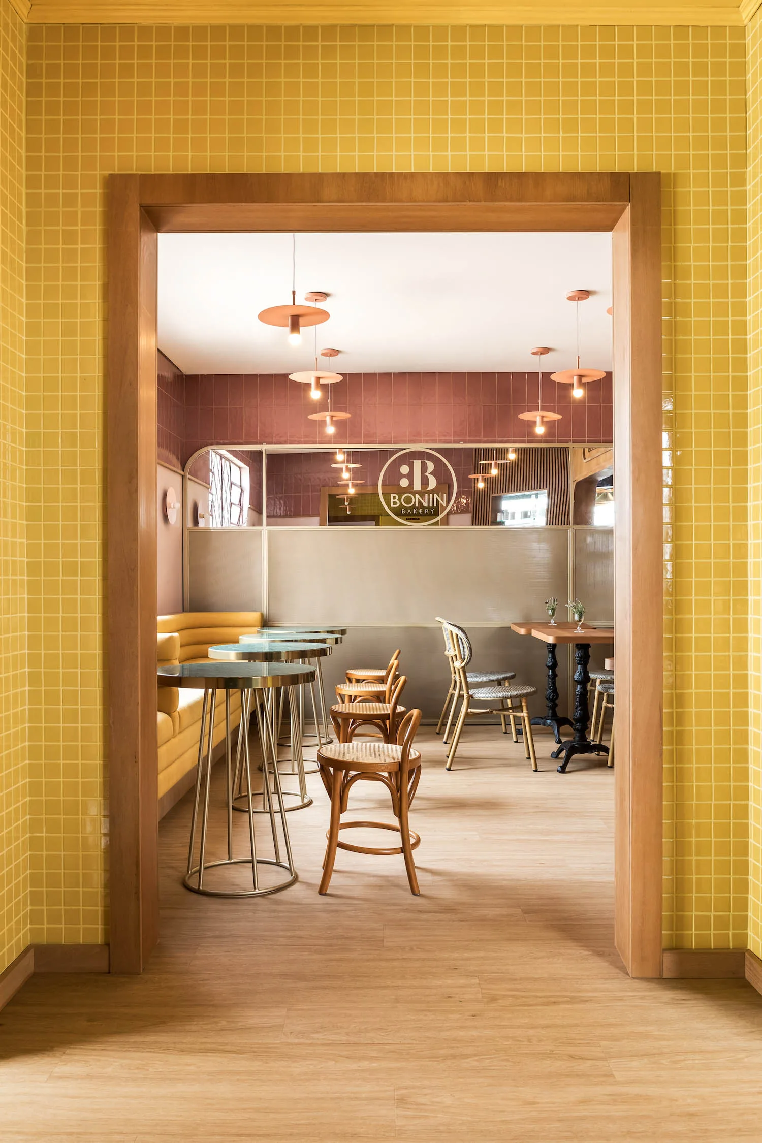 modern café interior with yellow tiled entrance, wooden frames, and copper pendant lighting., bakery via veneto, curitiba