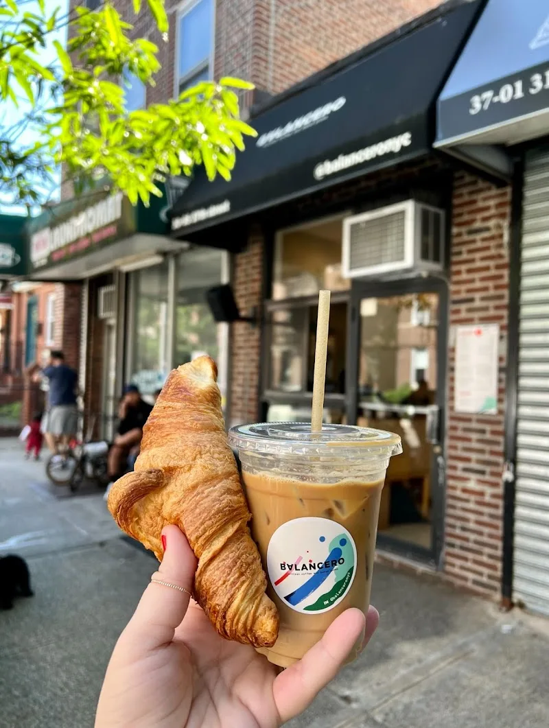 hand holding croissant and iced coffee drink on city street outside café., balancero, new york city