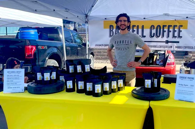 man at specialty coffee vendor booth with packaged coffee products displayed., barbell coffee company, hudson