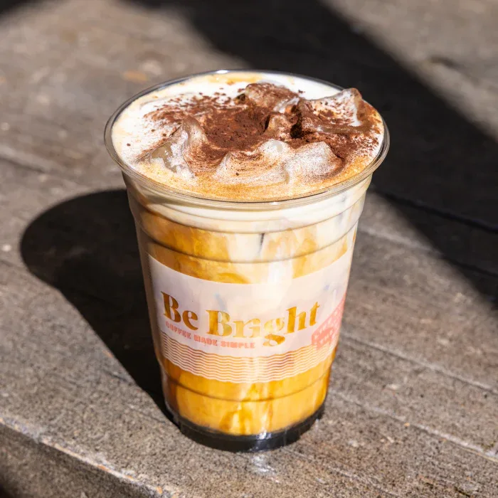 iced coffee drink with layered caramel, whipped cream, and cocoa powder topping., be bright coffee, los angeles