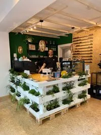 modern cafe counter built from white wooden pallets with green plants and dark wall backdrop., bean there, hamburg