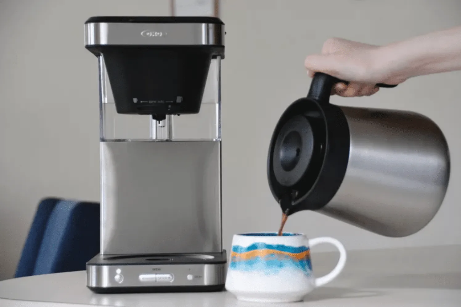person pouring coffee from thermal carafe into decorative mug beside single-serve brewer., beat coffee, reservoir