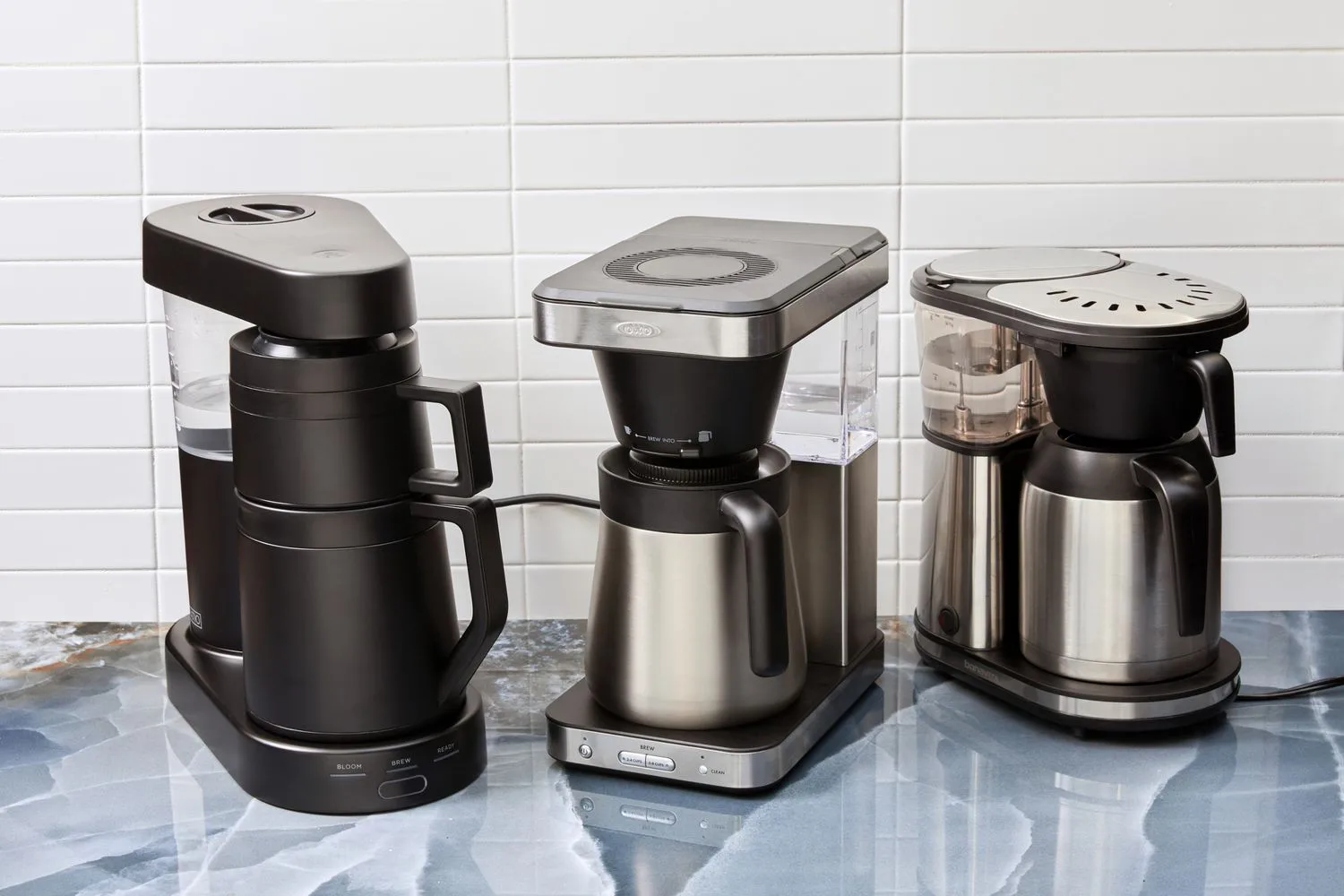 three modern coffee makers displayed on a countertop with white subway tile backsplash., beat coffee, reservoir