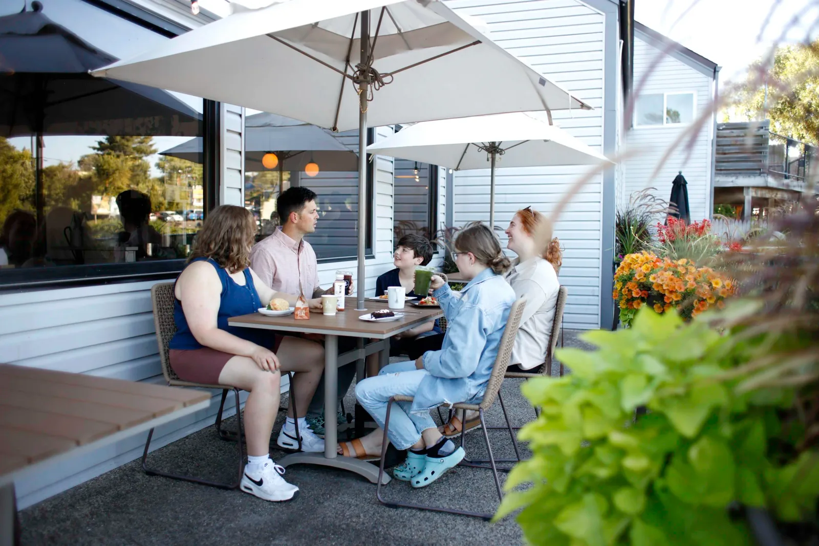 group of five people dining together on outdoor patio under umbrellas., bella goose coffee - cafe on the river, wisconsin del