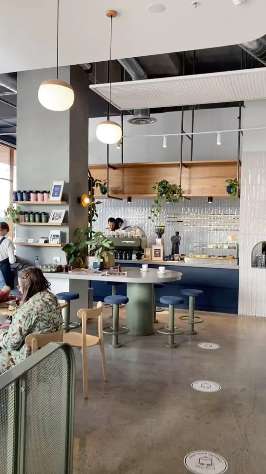 modern café interior with concrete floors, pendant lighting, and navy blue counter seating., bellboy cafe | brunswick cafe, b