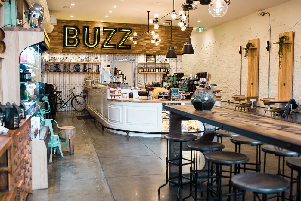 modern café interior with "buzz" neon sign and wooden counter seating., better buzz coffee point loma, san diego