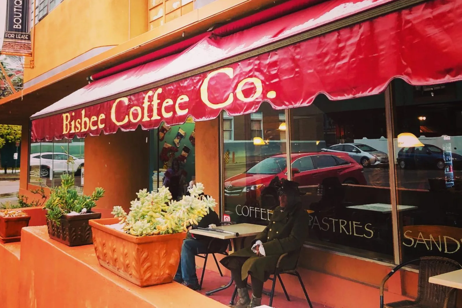 bisbee coffee co. storefront with red awning, outdoor seating, and white flowers., bisbee coffee company, arizona