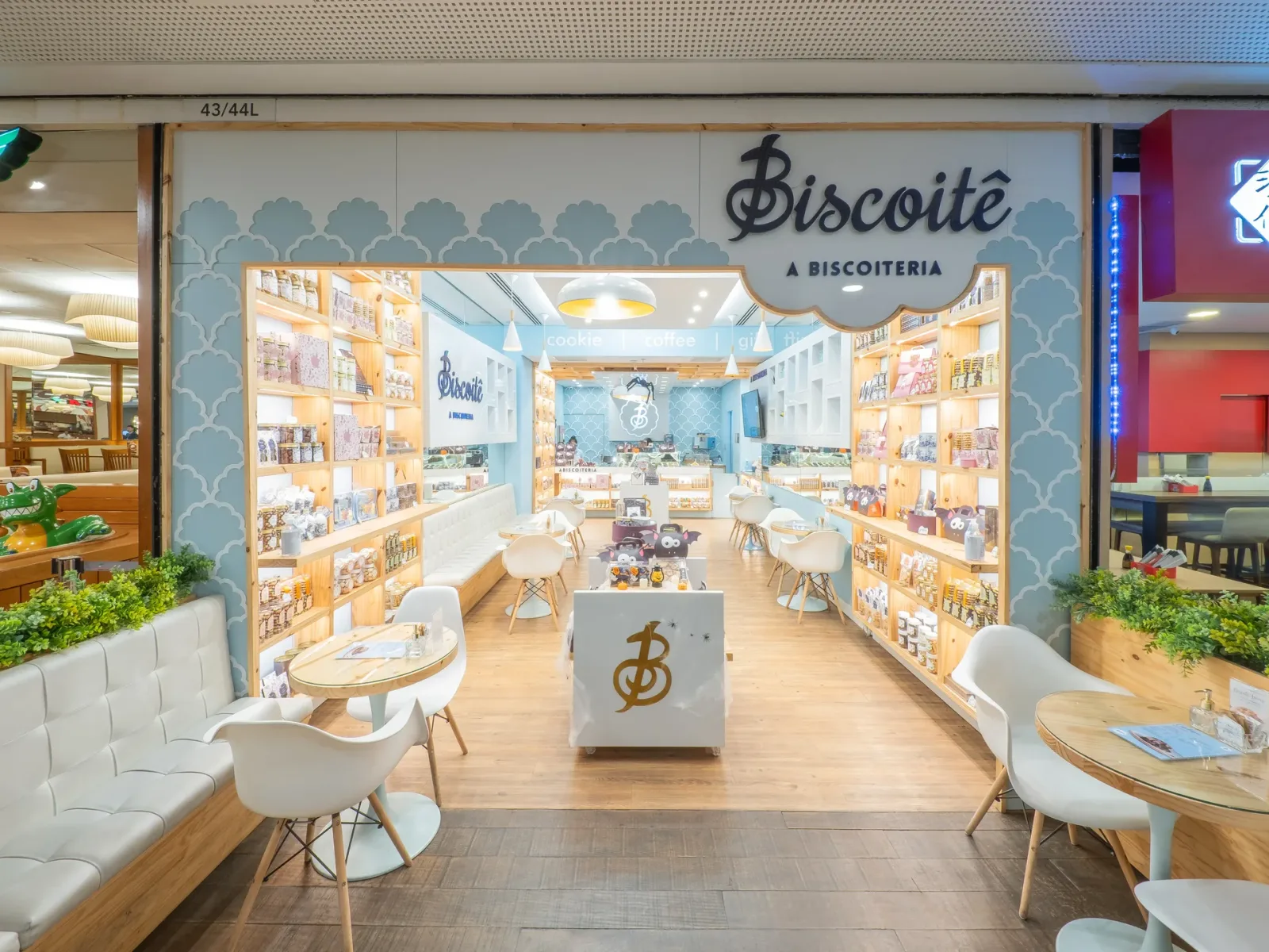 biscoite bakery storefront with light wood shelving, white chairs, and blue wall design., biscoitê a biscoiteria, são paulo