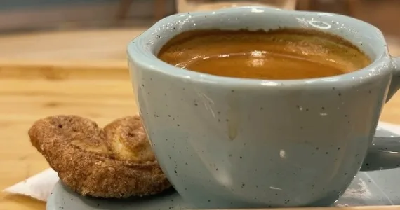 speckled ceramic cup of espresso beside a cinnamon-sugar cookie on wooden surface., biscoitê a biscoiteria, são paulo
