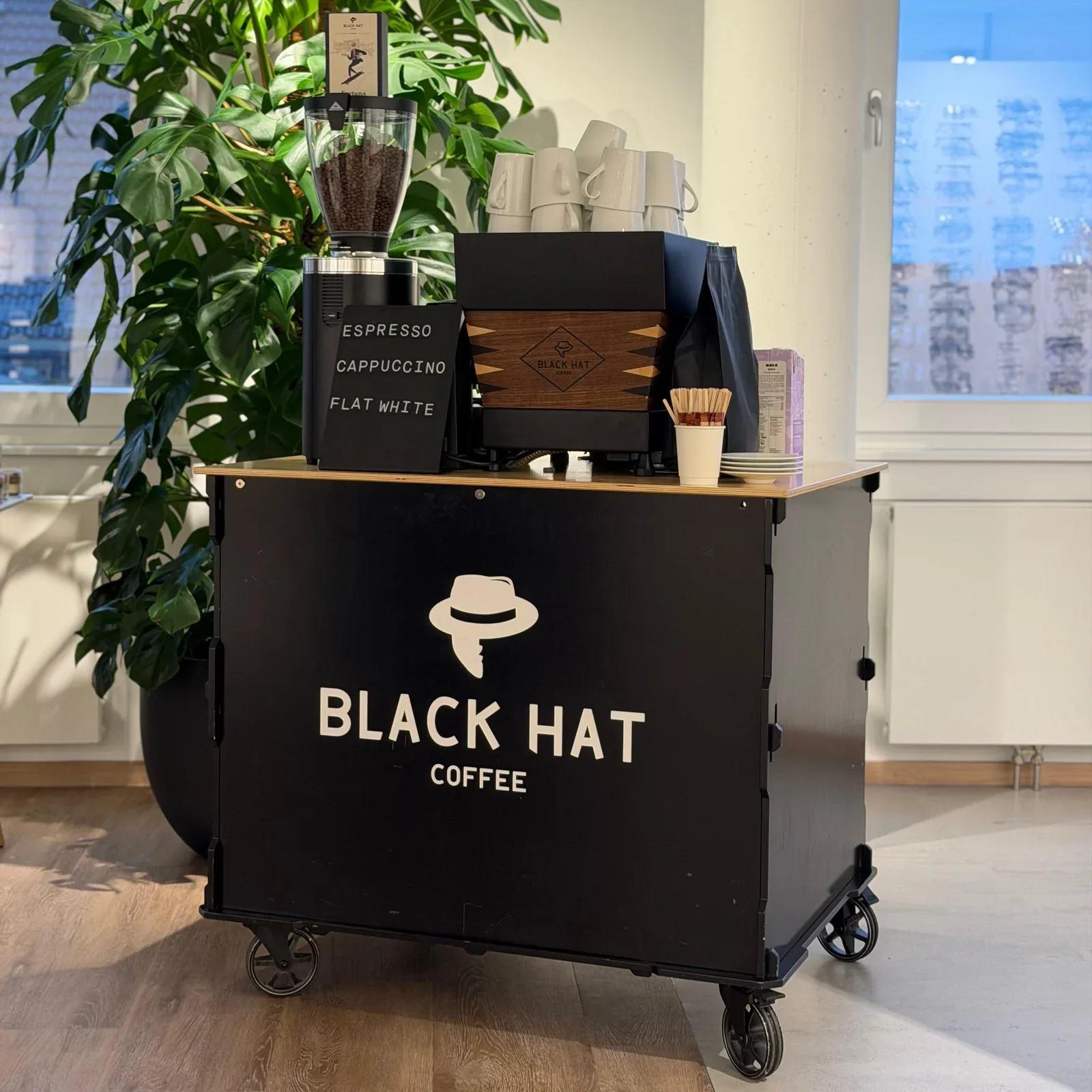 black hat coffee mobile cart with espresso machine, cups, and green plant decor., black hat coffee - specialty espresso bar, 