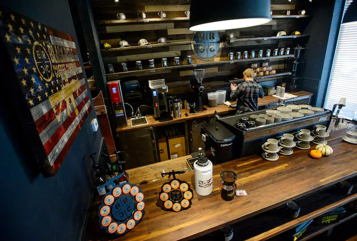 coffee shop counter with brewing equipment, cups, and patriotic american flag wall decor., black rifle coffee company, salt l