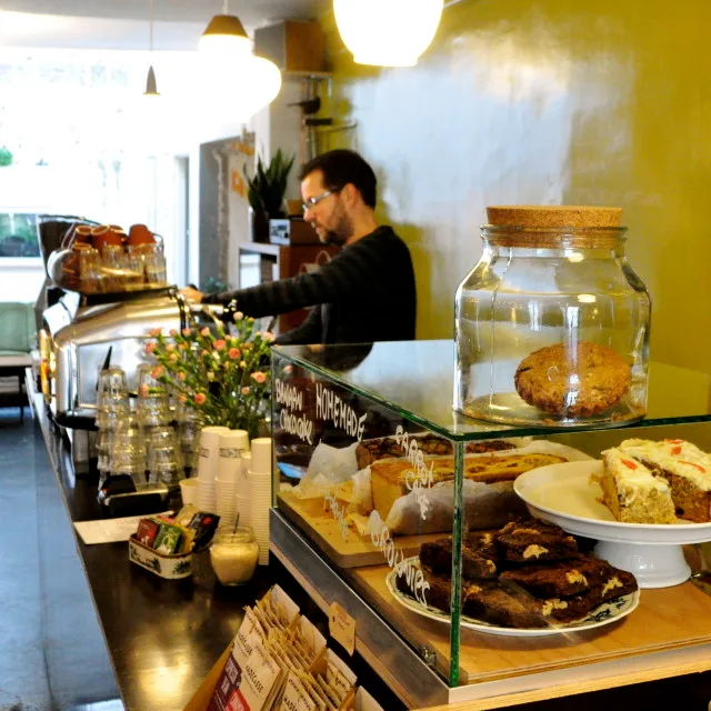 bakery counter with pastries, cookies, and a man working behind the display., blackbird coffee & vintage, utrecht