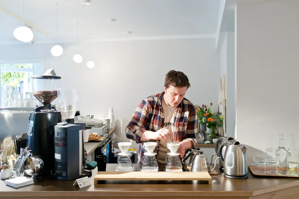 barista in plaid shirt preparing pour-over coffee at modern café counter., blom, bergen