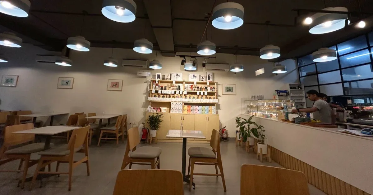modern café interior with wooden furniture, pendant lighting, and service counter., blue tokai coffee roasters | chandigarh 3