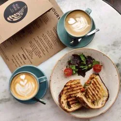breakfast spread with waffles, salad, and two latte art cappuccinos on marble table., blue tokai coffee roasters | vasant vih