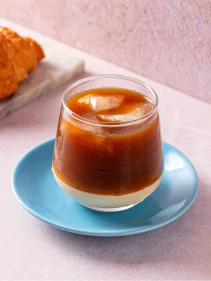 layered coffee drink with cream on blue saucer, pastry visible background., blue tokai coffee roasters | zirakpur, gazipur, z