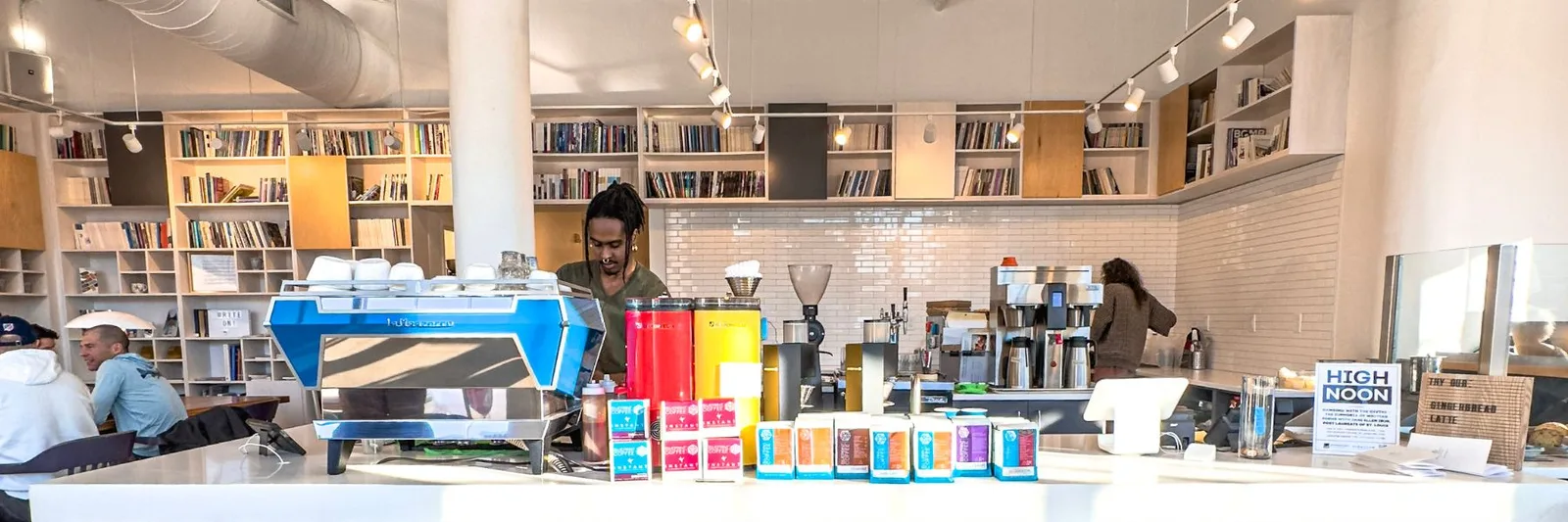 modern café counter with espresso machine, colorful product boxes, and barista staff., blueprint coffee - delmar, st. louis