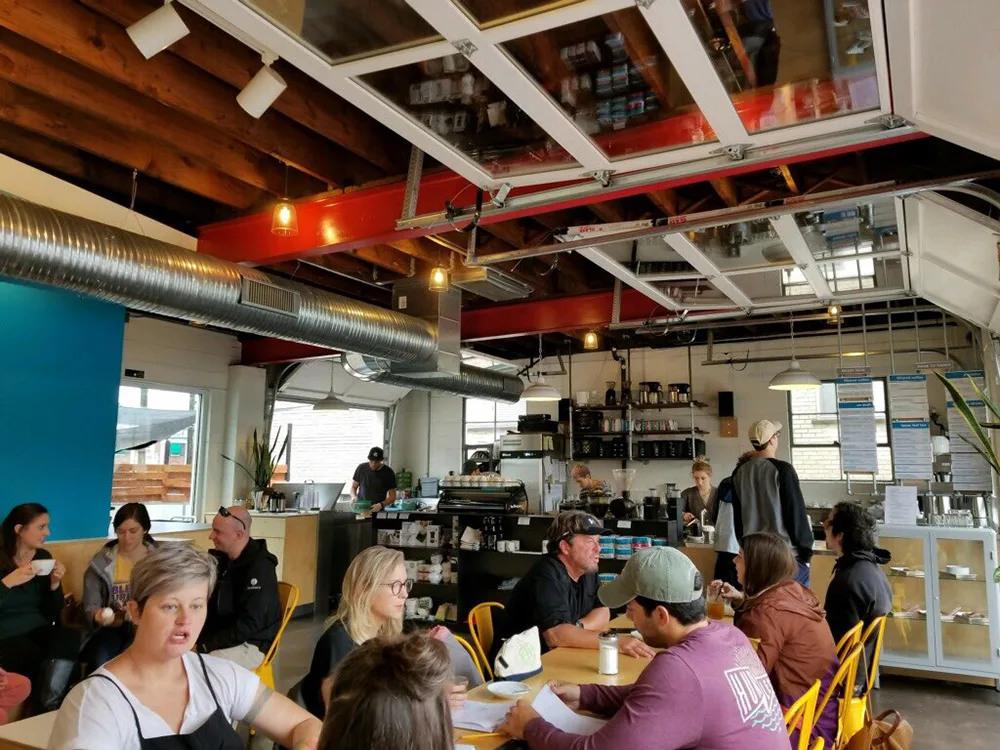 busy modern café interior with yellow chairs, exposed red beams, and industrial ceiling., blueprint coffee - watson, st. loui