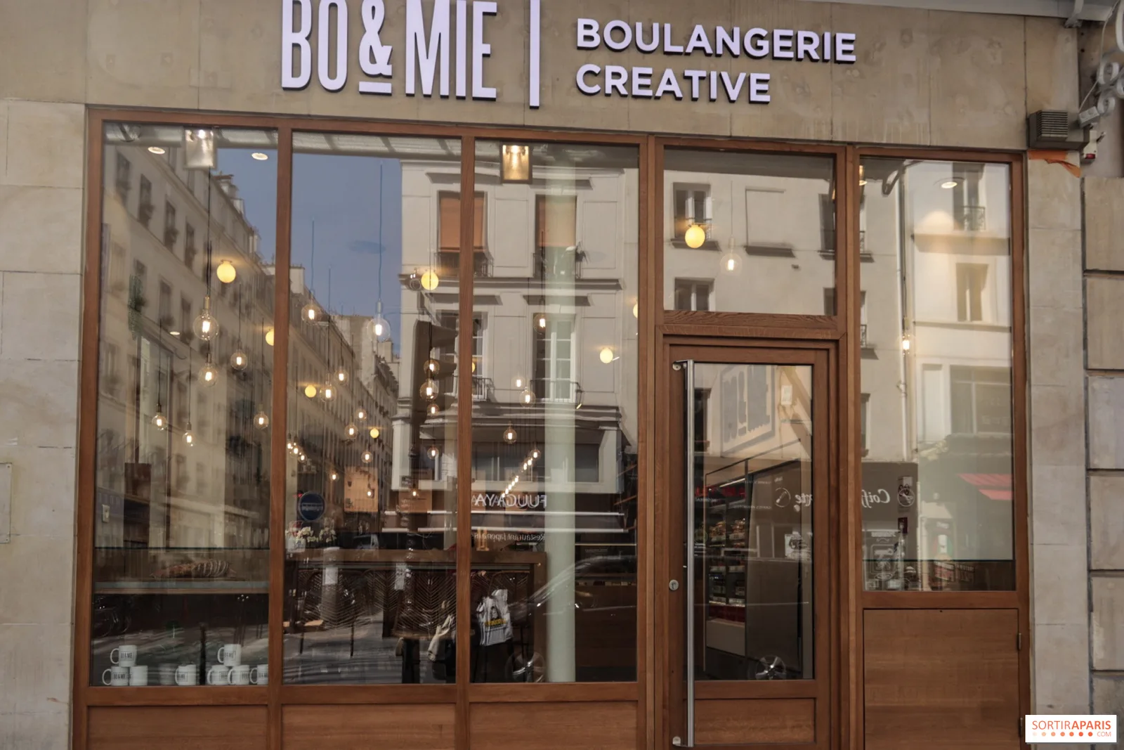 modern bakery storefront with wooden frames, illuminated hanging lights, paris street reflection., bo&mie - saint martin, par