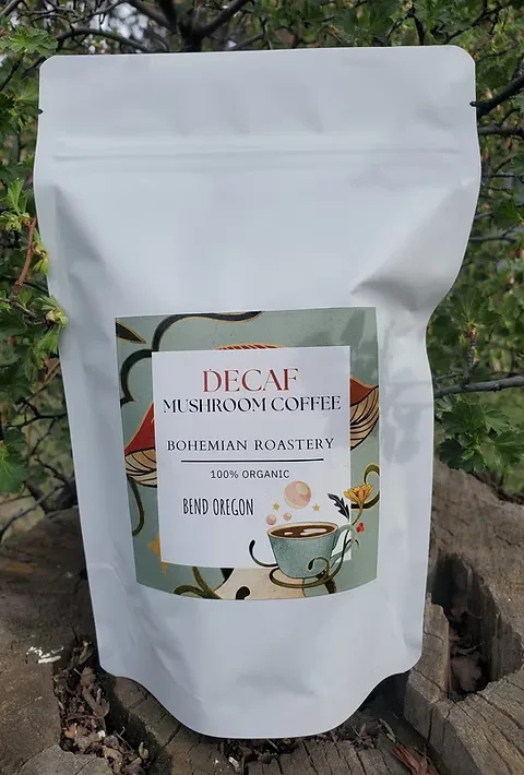 white pouch of decaf mushroom coffee by bohemian roastery on wooden surface with greenery., bohemian roastery, bend