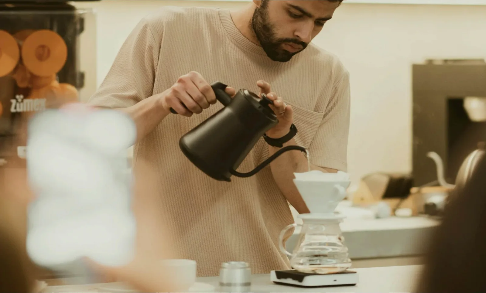 man pouring hot water from black kettle into white cup on table., boscon | specialty coffee roasters & brunch, valència