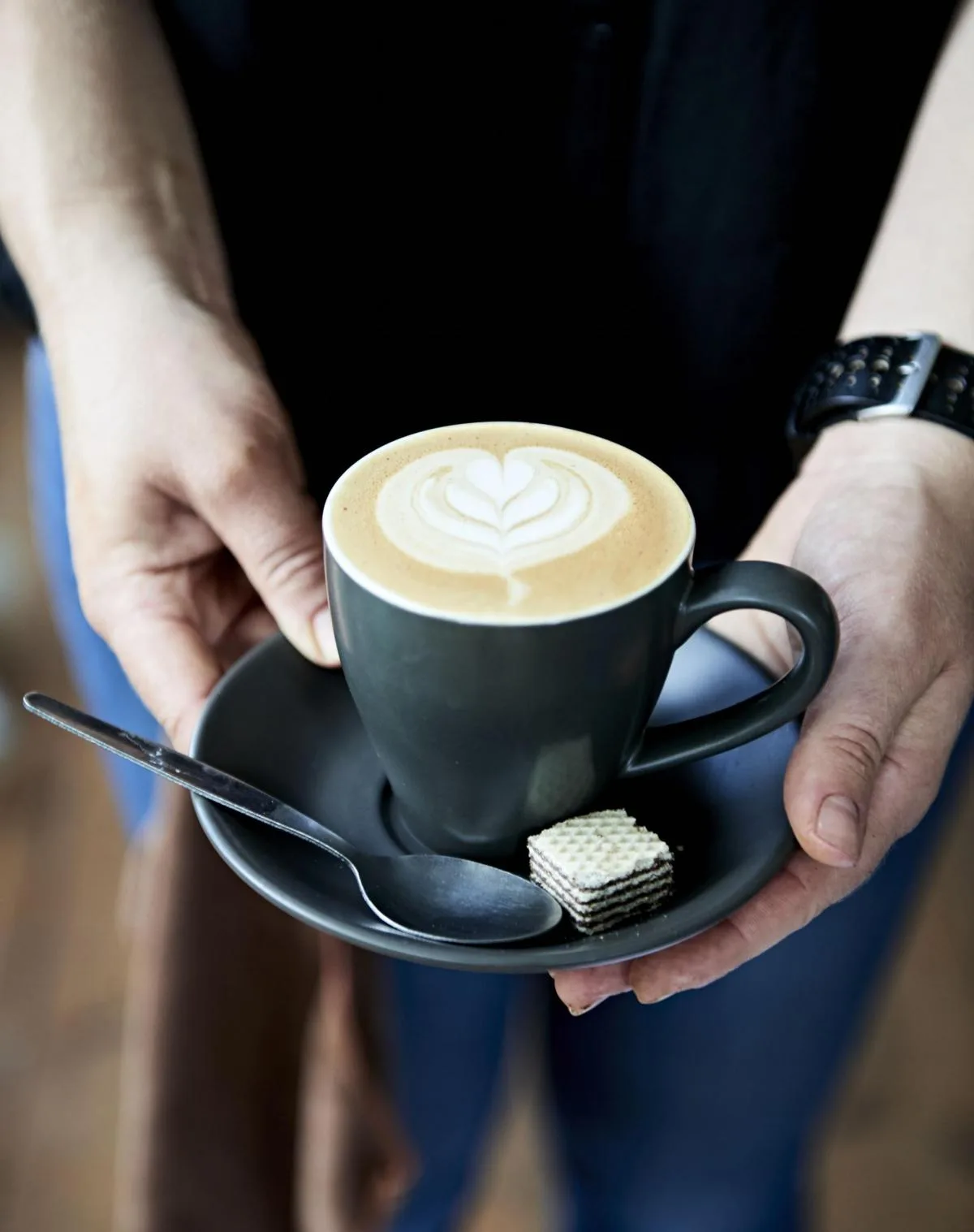 person holding black mug with latte art heart design and wafer cookie., brazier coffee roasters, taunton