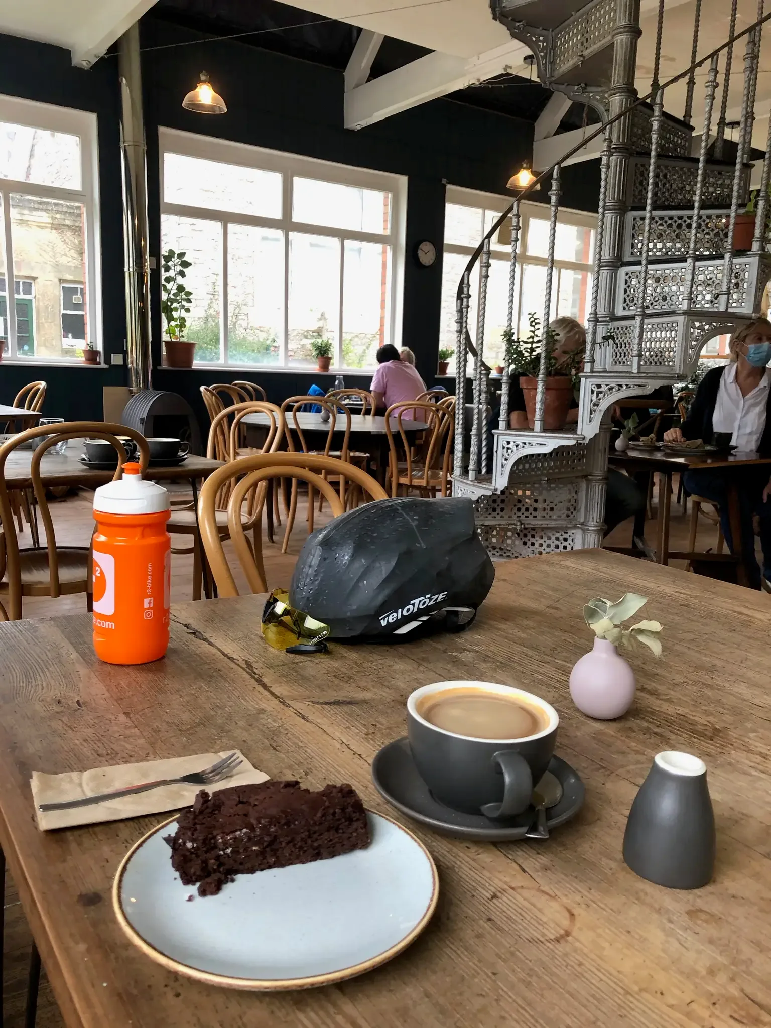 bicycle helmet and chocolate cake at café table with coffee and water bottle., brazier coffee roasters, taunton
