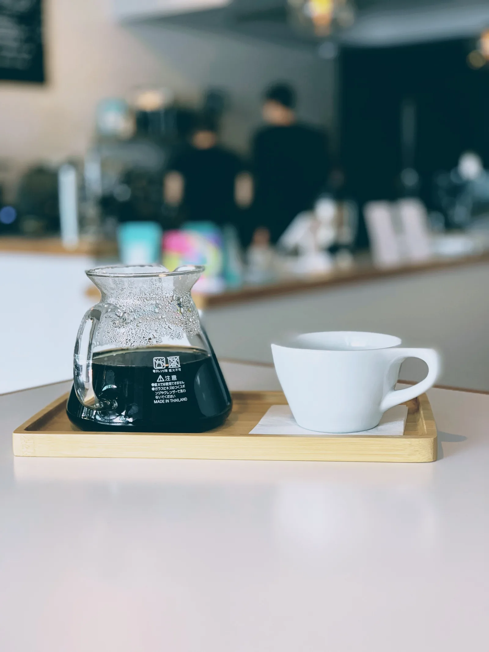 coffee carafe with fresh brew and white mug on wooden tray, cafe interior blurred., breaking wave coffee, sarasota