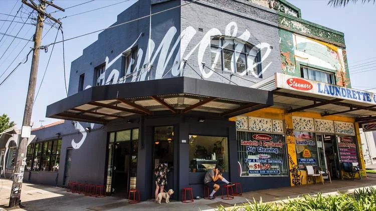 modern storefront with dark facade, mural art, and adjacent laundromat signage visible., brighter coffee, stanmore